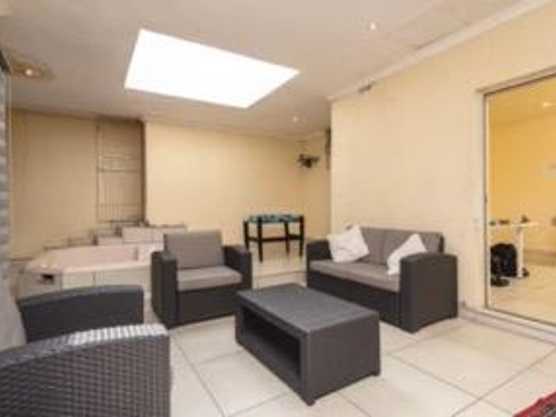 A covered patio area featuring tiled flooring, a large skylight for natural light, and direct access to an adjacent room through sliding glass doors.