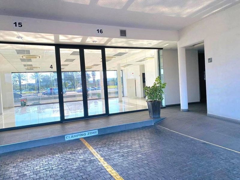 Modern retail entrance featuring a glass storefront, paved exterior access area, and clean, professional finishes suitable for a commercial showroom or office space.