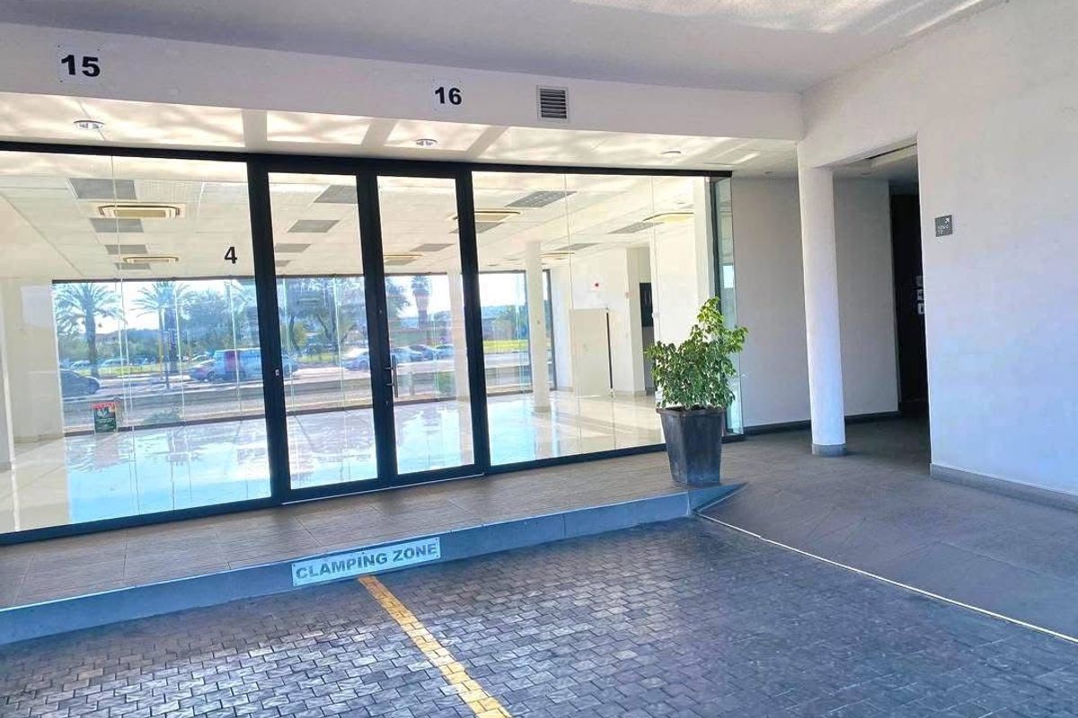 Modern retail entrance featuring a glass storefront, paved exterior access area, and clean, professional finishes suitable for a commercial showroom or office space.