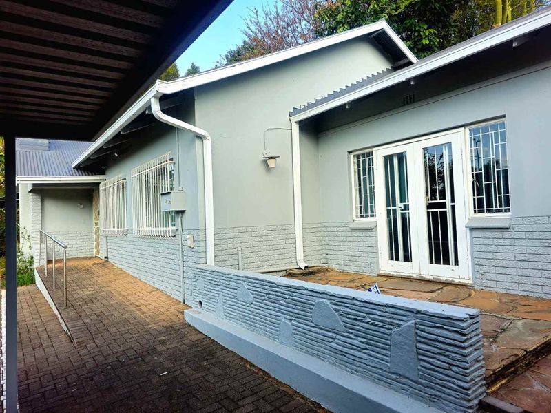 Rear exterior view featuring a paved walkway, stone patio area, and secure double door access to the home.