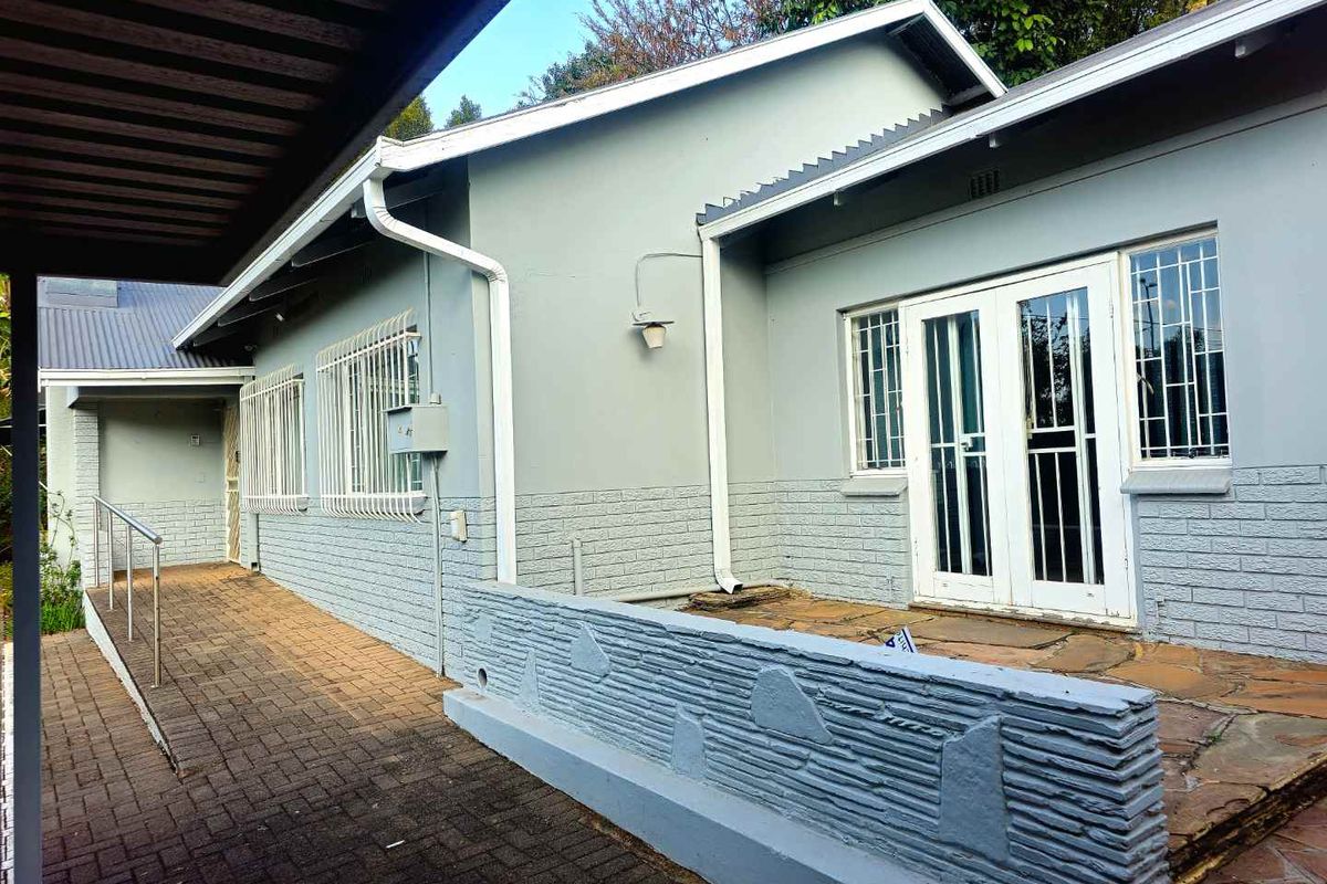 Rear exterior view featuring a paved walkway, stone patio area, and secure double door access to the home.