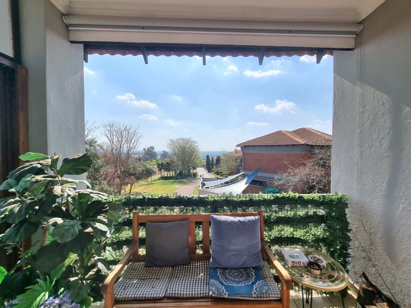 A covered balcony featuring a retractable awning and scenic views of the surrounding estate and landscape.