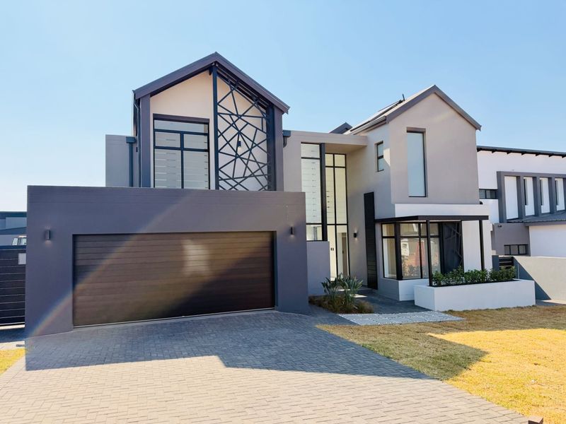 Modern double-story residential home featuring a contemporary facade, paved driveway, integrated double garage, and striking architectural metal detailing.