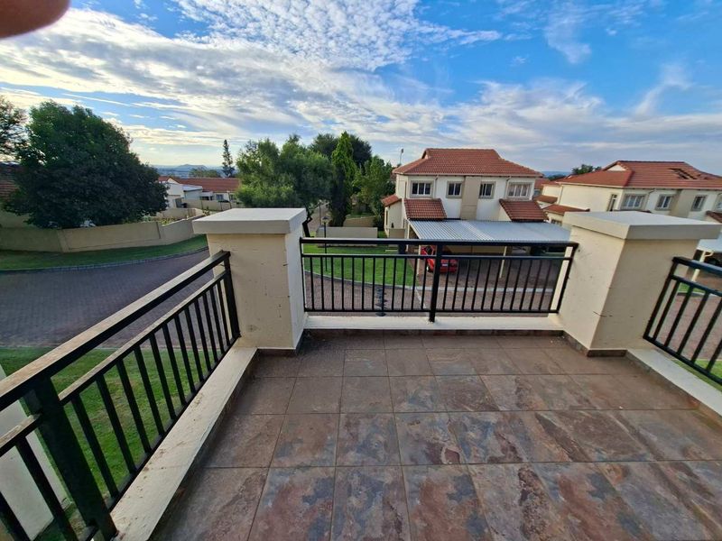 A spacious balcony featuring durable tiled flooring and a secure metal balustrade, offering an elevated view of the surrounding residential estate.