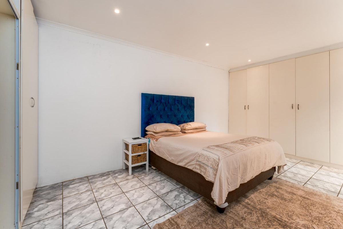 A bedroom featuring built-in cupboards, recessed ceiling lighting, and tiled flooring.