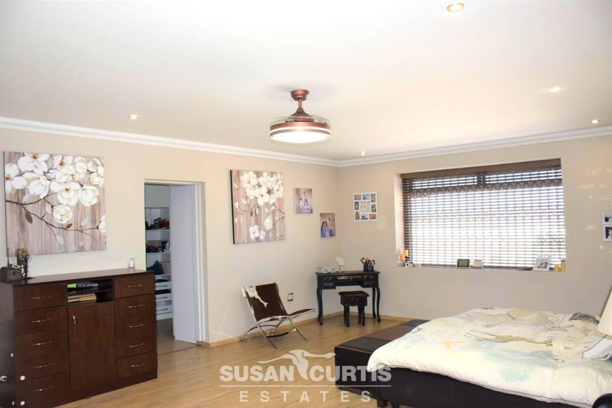 Spacious bedroom featuring light wood-look flooring, recessed ceiling lighting, a central ceiling fan, and an adjoining walk-in closet area.