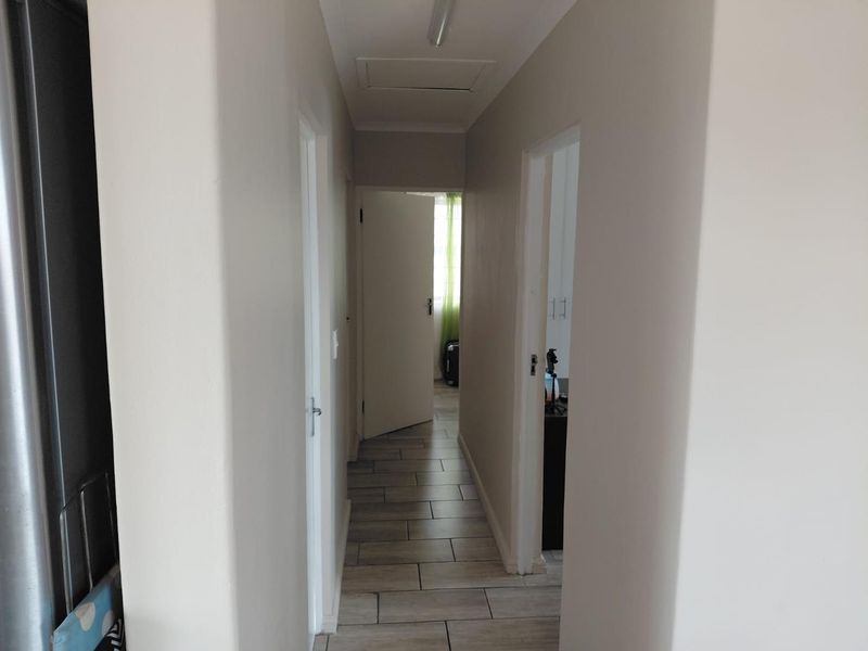 A functional hallway featuring neutral wall finishes and tiled flooring, providing access to multiple rooms within the home.