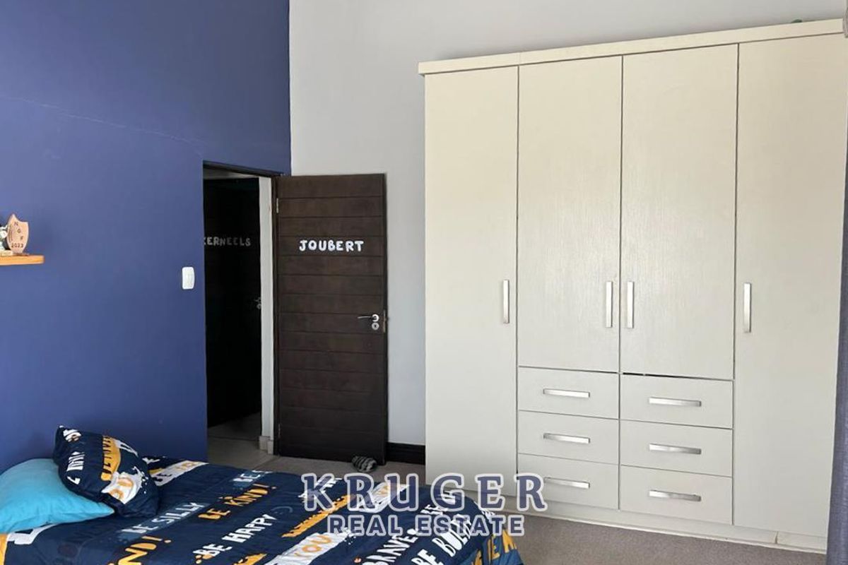 A bedroom featuring built-in cupboards with integrated drawers and a dark wood interior door.