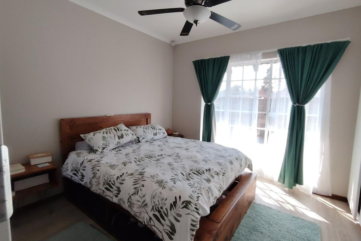 A well-lit bedroom featuring a ceiling fan and large glass sliding doors that provide access to the exterior.