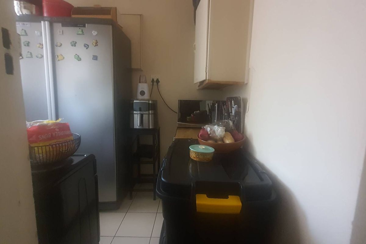 A compact kitchen area featuring tiled flooring and built-in wall cabinetry, providing functional storage space within the apartment.