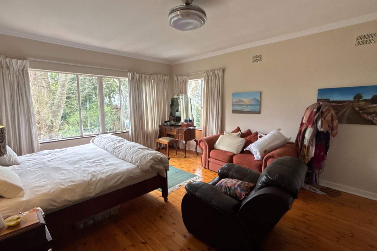 Spacious bedroom featuring polished hardwood flooring, large windows providing natural light, and classic coving details.