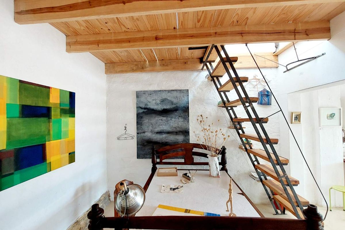 A unique interior space featuring exposed timber ceiling beams and a striking industrial-style open staircase with wooden treads.