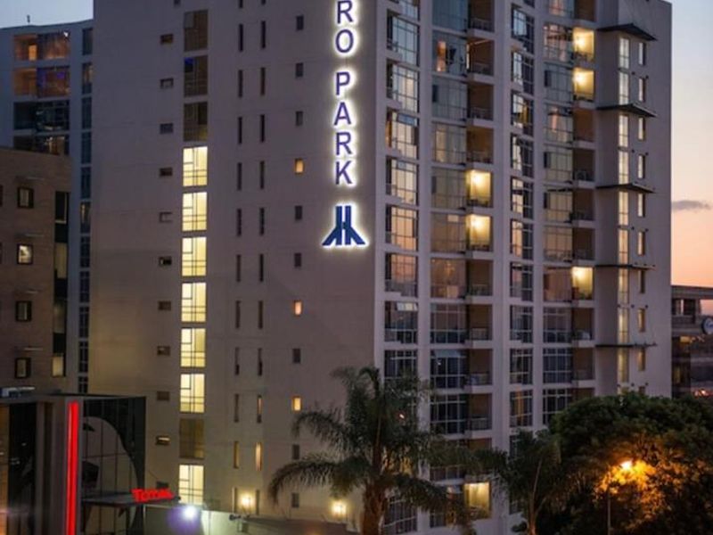 Exterior view of the Hydro Park penthouse building at dusk, showcasing the modern facade, illuminated signage, and surrounding street-level infrastructure.