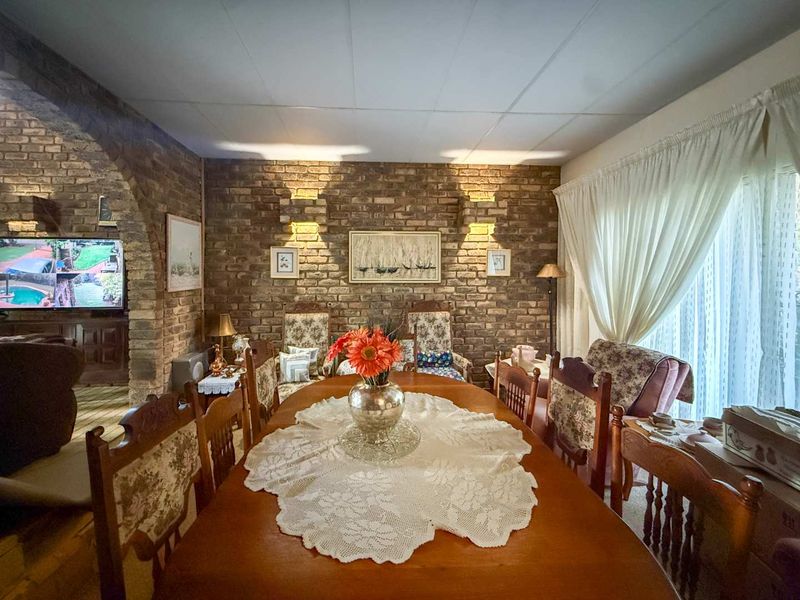Dining room featuring a prominent exposed brick feature wall, brick archway, and recessed lighting, creating a traditional and textured living space.