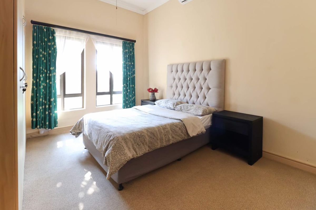 A well-maintained bedroom featuring neutral carpeting, built-in cabinetry, and large windows that provide ample natural light.
