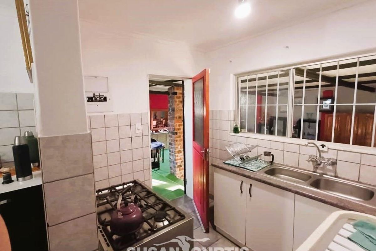Functional kitchen featuring a double sink, gas stove, and tiled splashbacks with direct access to an adjacent living area.