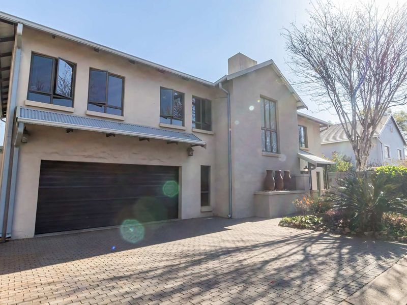 Front elevation of a modern two-story house featuring a paved driveway, integrated double garage, and clean plastered exterior finishes.