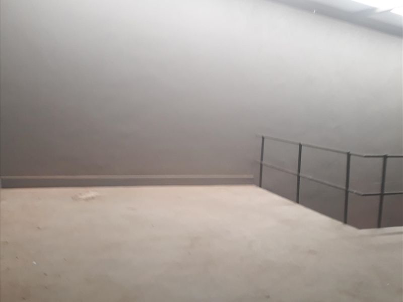 An open industrial utility space featuring concrete flooring, metal safety railings, and overhead industrial lighting.