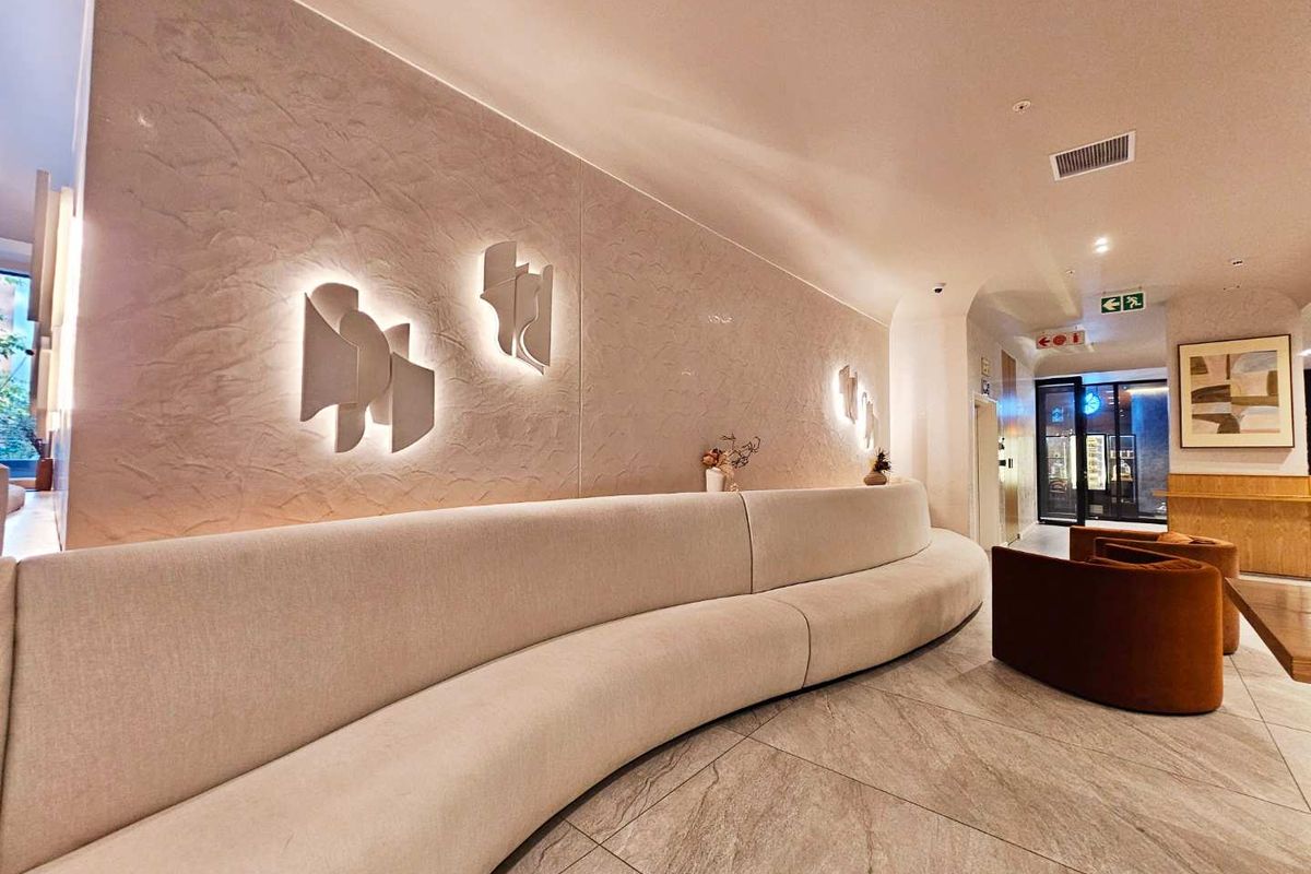 Modern apartment lobby or communal lounge area featuring textured feature walls, integrated wall lighting, and large format floor tiles.