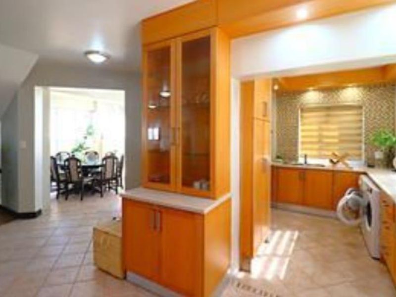 Open plan kitchen and dining area featuring warm-toned wooden cabinetry, tiled flooring, and a mosaic backsplash, creating a functional and connected living space.