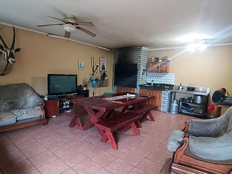 Open plan living and dining area featuring a brick fireplace, tiled flooring, and integrated cabinetry, offering a functional space with potential for modernization.