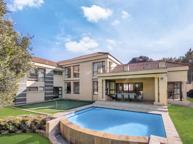 Spacious rear exterior featuring a swimming pool, covered patio, and a private putting green set against a well-maintained two-story residence.