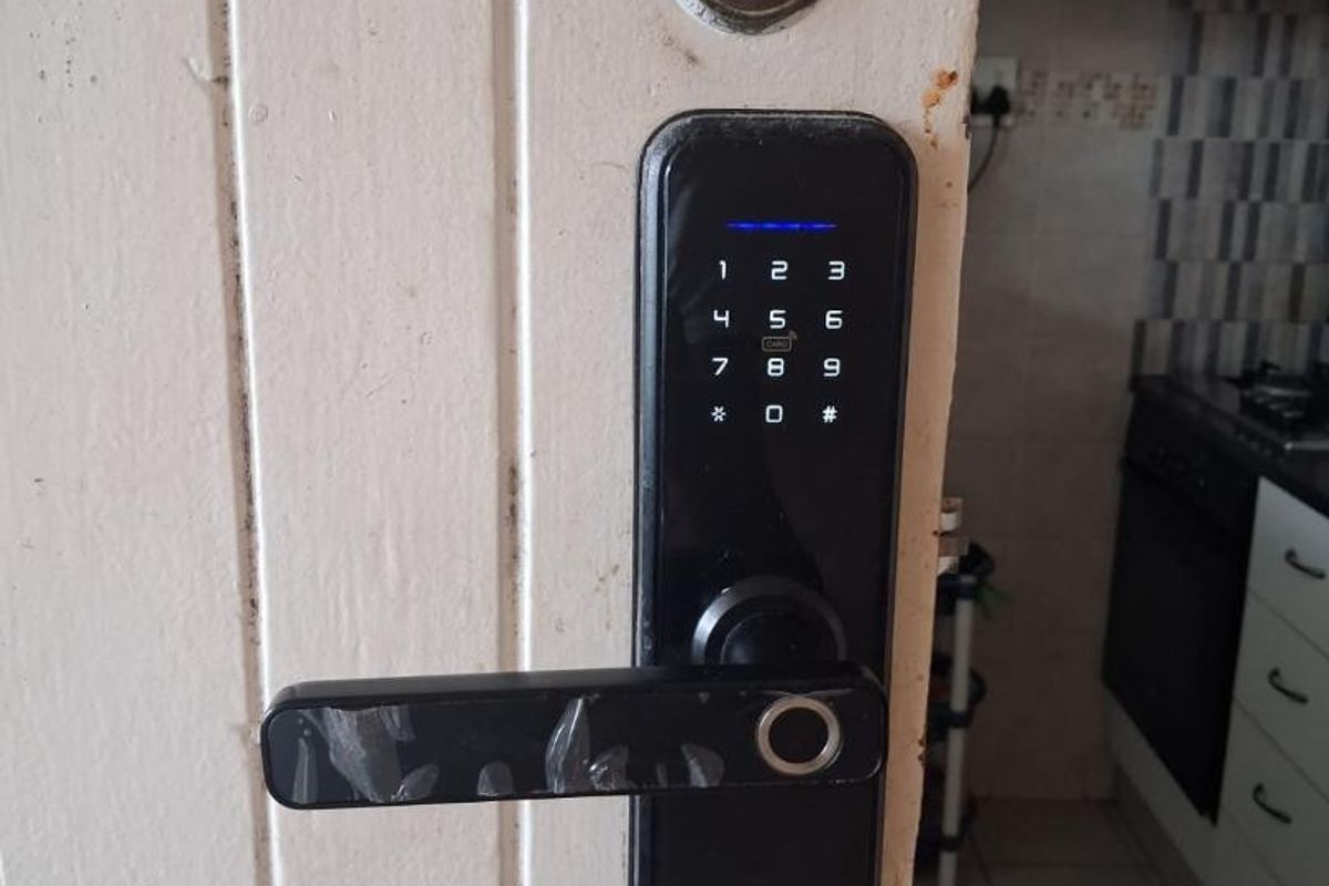 Close-up view of a digital smart lock installed on a white interior door, with a glimpse of the kitchen area in the background.