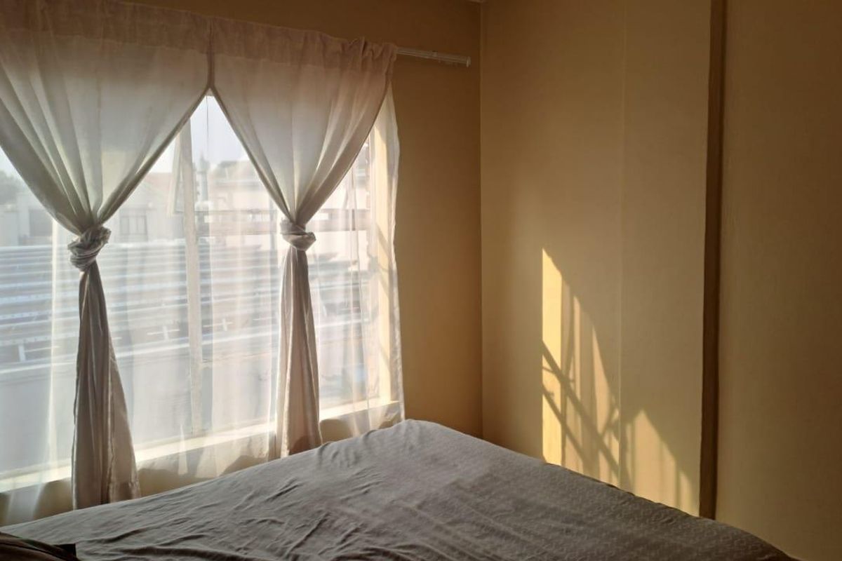 A simple bedroom featuring a large window with natural light and neutral wall finishes.