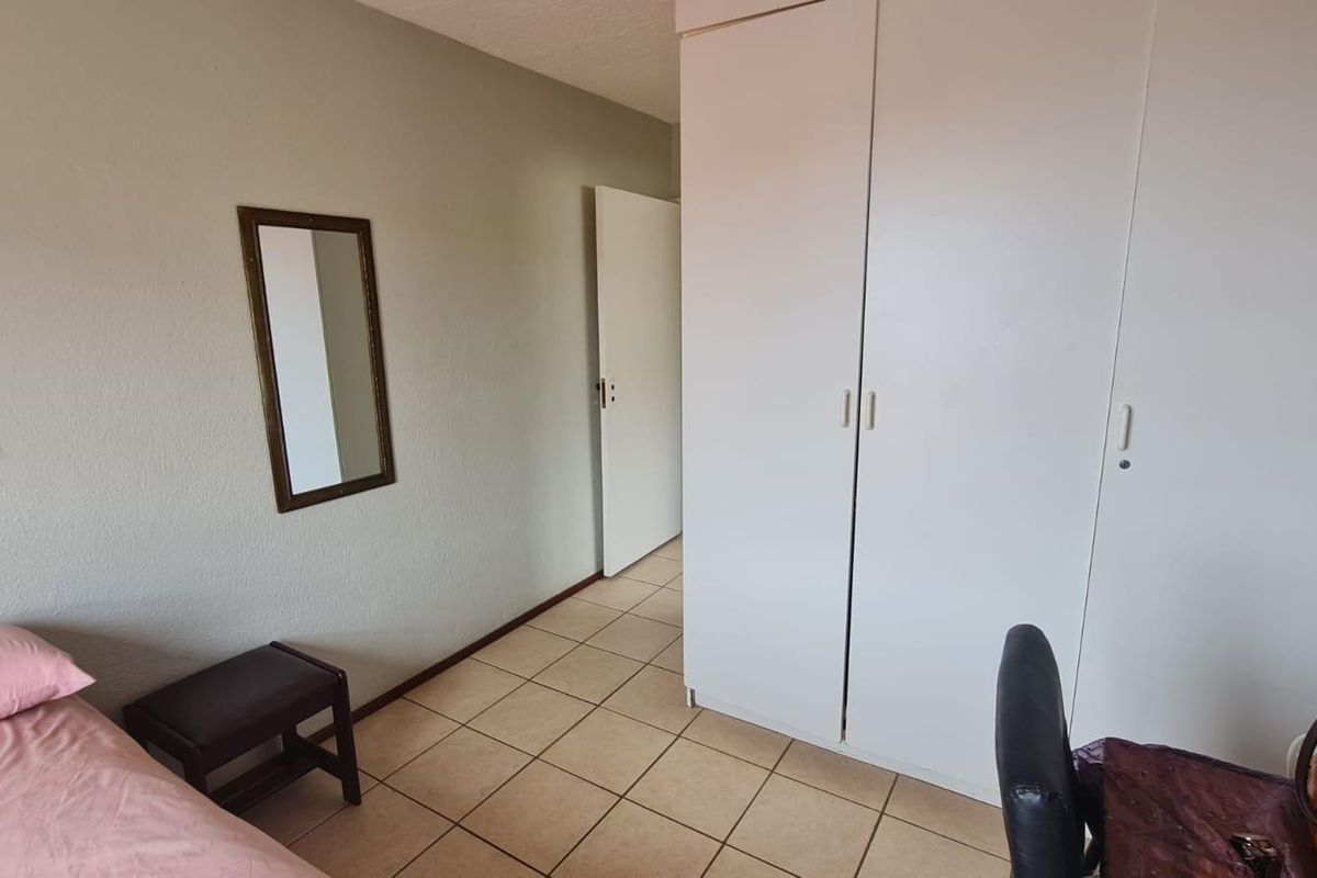 A bedroom featuring tiled flooring and built-in cupboards, providing functional storage space within the apartment.