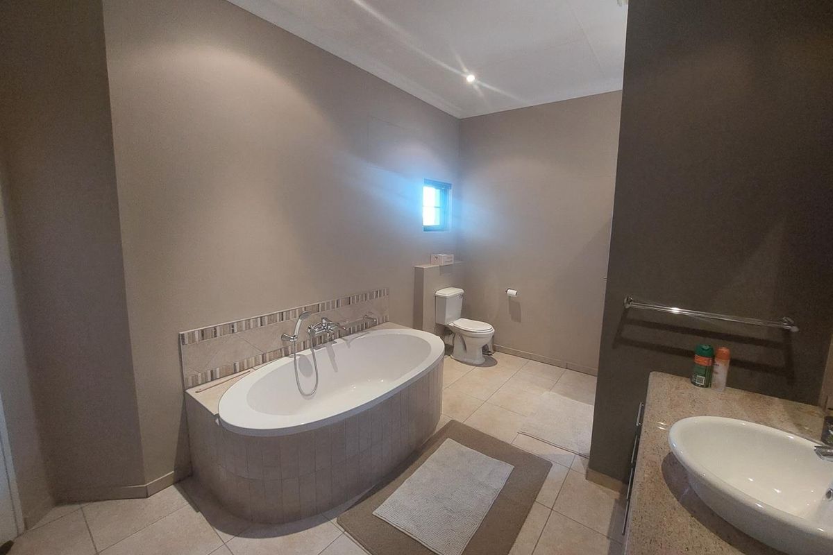 A well-maintained bathroom featuring a built-in bathtub with tiled surround, a separate toilet, and a vanity with a basin.
