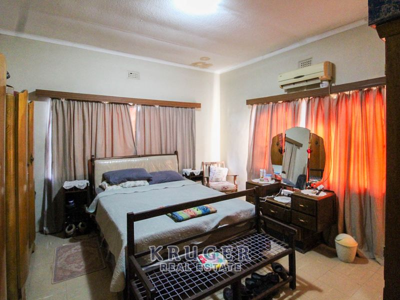 A bedroom featuring tiled flooring, cornicing, and a wall-mounted air conditioning unit, showing signs of ceiling water damage.