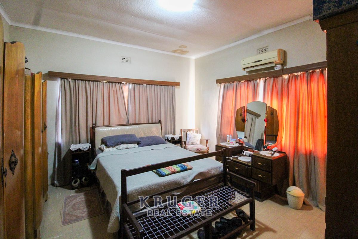 A bedroom featuring tiled flooring, cornicing, and a wall-mounted air conditioning unit, showing signs of ceiling water damage.