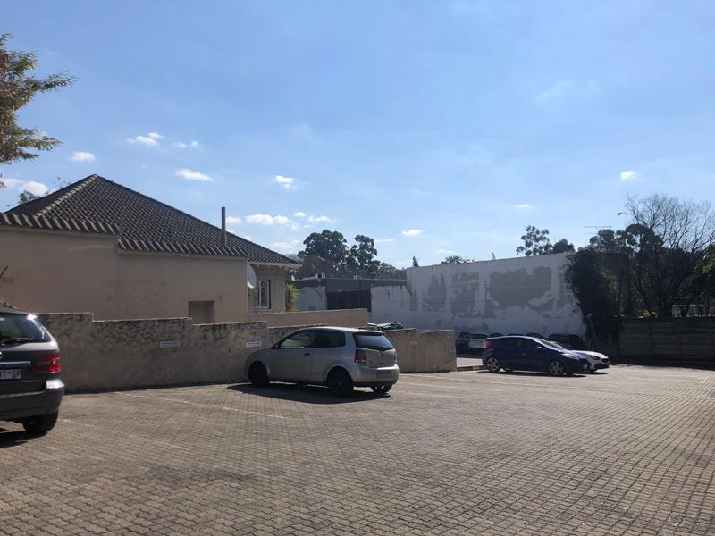 Exterior view of the office property featuring a paved parking area and boundary wall with visible exterior wall maintenance required.