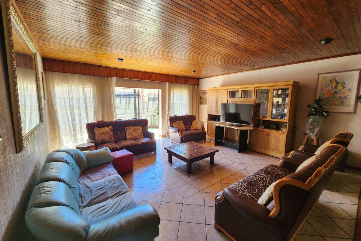 Spacious living room featuring tiled flooring and a distinctive timber-clad ceiling, providing a traditional aesthetic with direct access to the exterior.