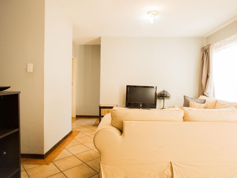 A living room area featuring neutral wall tones and tiled flooring, providing a functional space for relaxation.