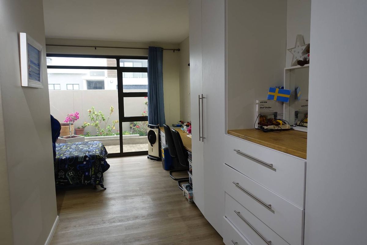 A well-lit bedroom featuring built-in cabinetry with integrated desk space and large sliding glass doors providing direct access to a private patio area.