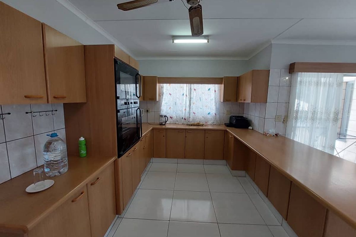 A functional kitchen featuring extensive wooden cabinetry, built-in double ovens, tiled flooring, and ample countertop workspace.