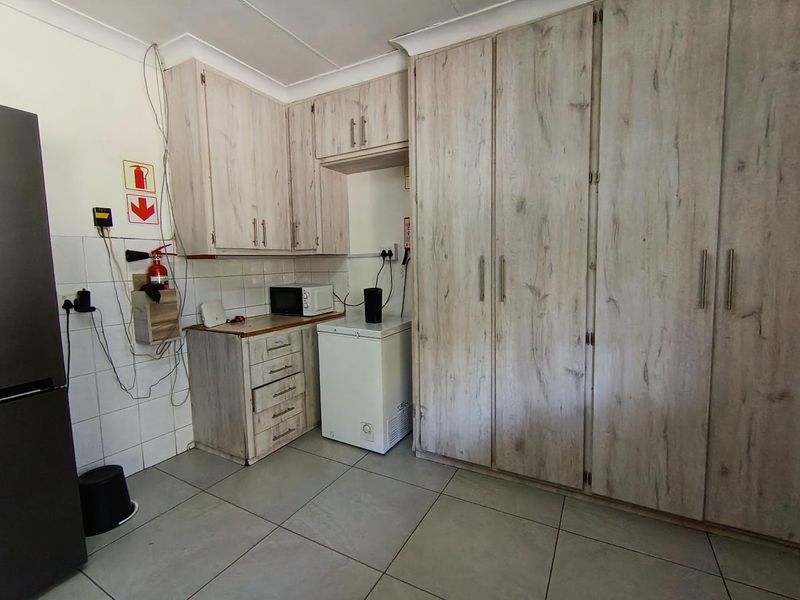 A functional scullery area featuring extensive built-in cabinetry, tiled flooring, and a tiled splashback, providing ample storage and utility space.