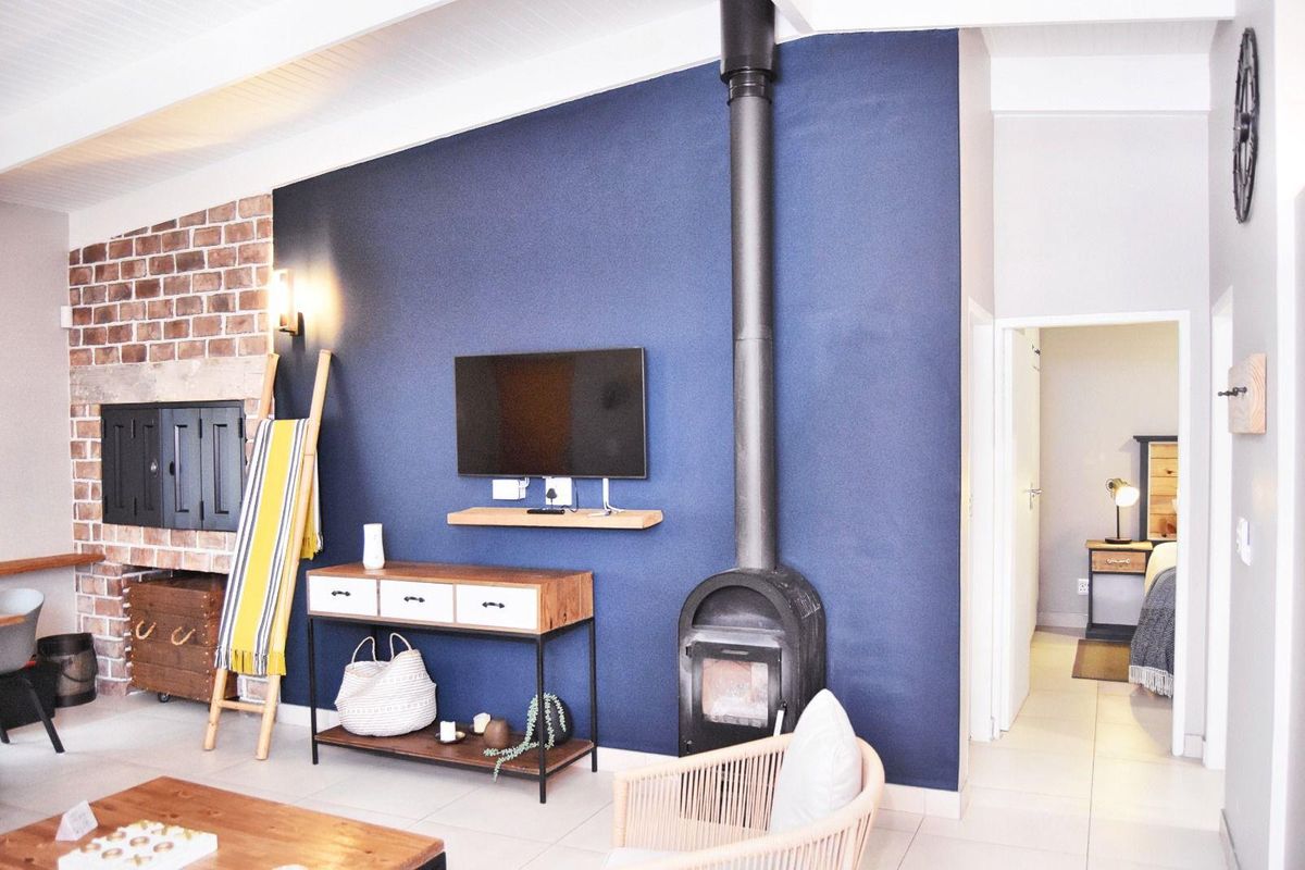Living room featuring a striking navy accent wall, a built-in brick fireplace, and a modern freestanding wood-burning stove with exposed flue.