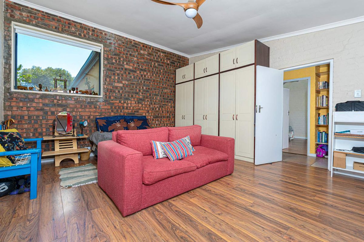 A bedroom featuring a prominent exposed brick feature wall, built-in floor-to-ceiling cabinetry, and wood-look laminate flooring.