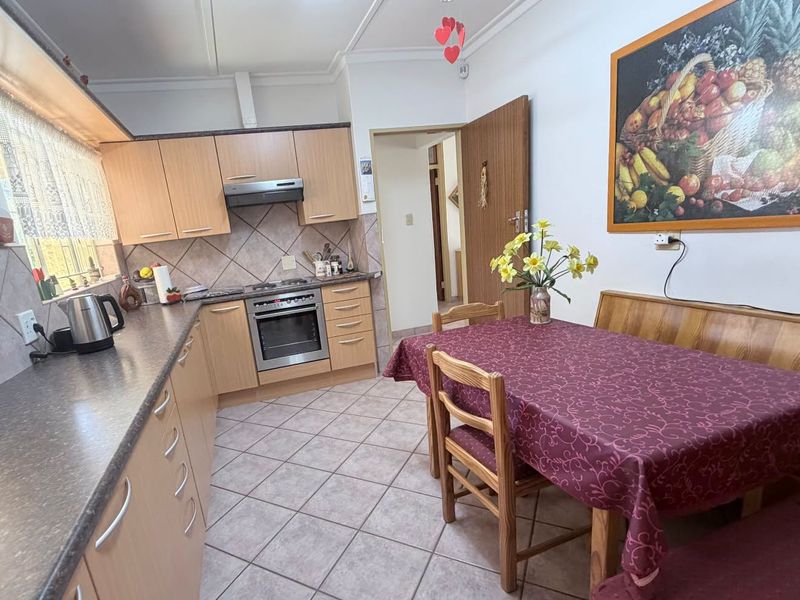 Open-plan kitchen and dining area featuring laminate cabinetry, built-in oven, extractor fan, tiled backsplash, and neutral floor tiles.