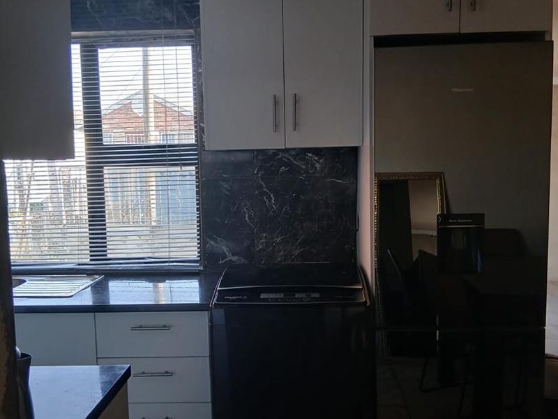 Compact kitchen featuring built-in cabinetry, stone countertops, and tiled backsplash, showing visible signs of ceiling water damage requiring repair.