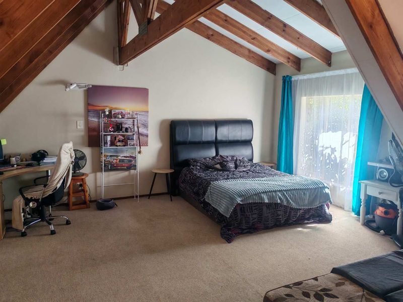 Spacious bedroom featuring a vaulted ceiling with exposed timber rafters and a large sliding glass door providing natural light.