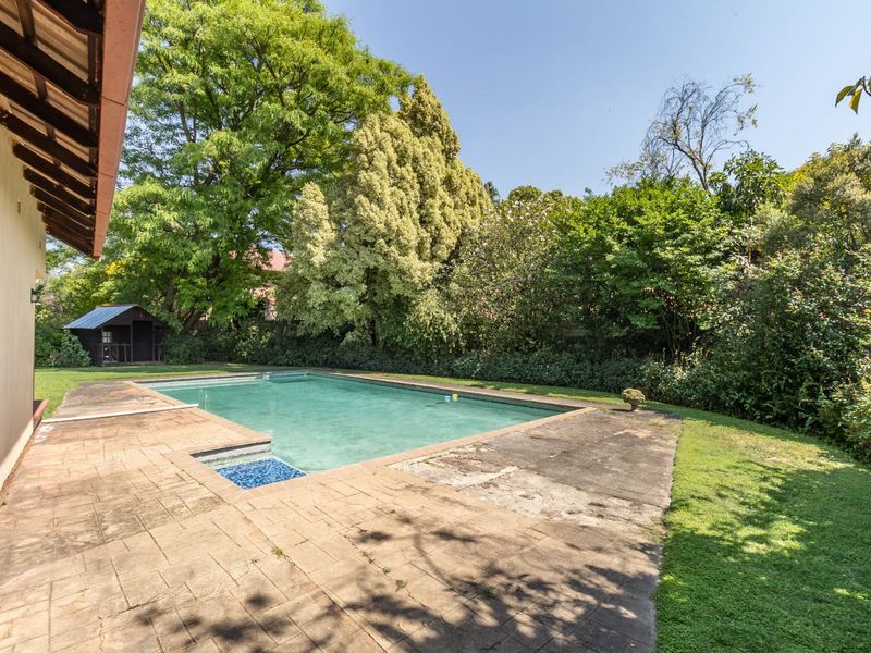 Outdoor pool area featuring a swimming pool, paved surround, and established garden setting, providing a private space for relaxation and recreation.