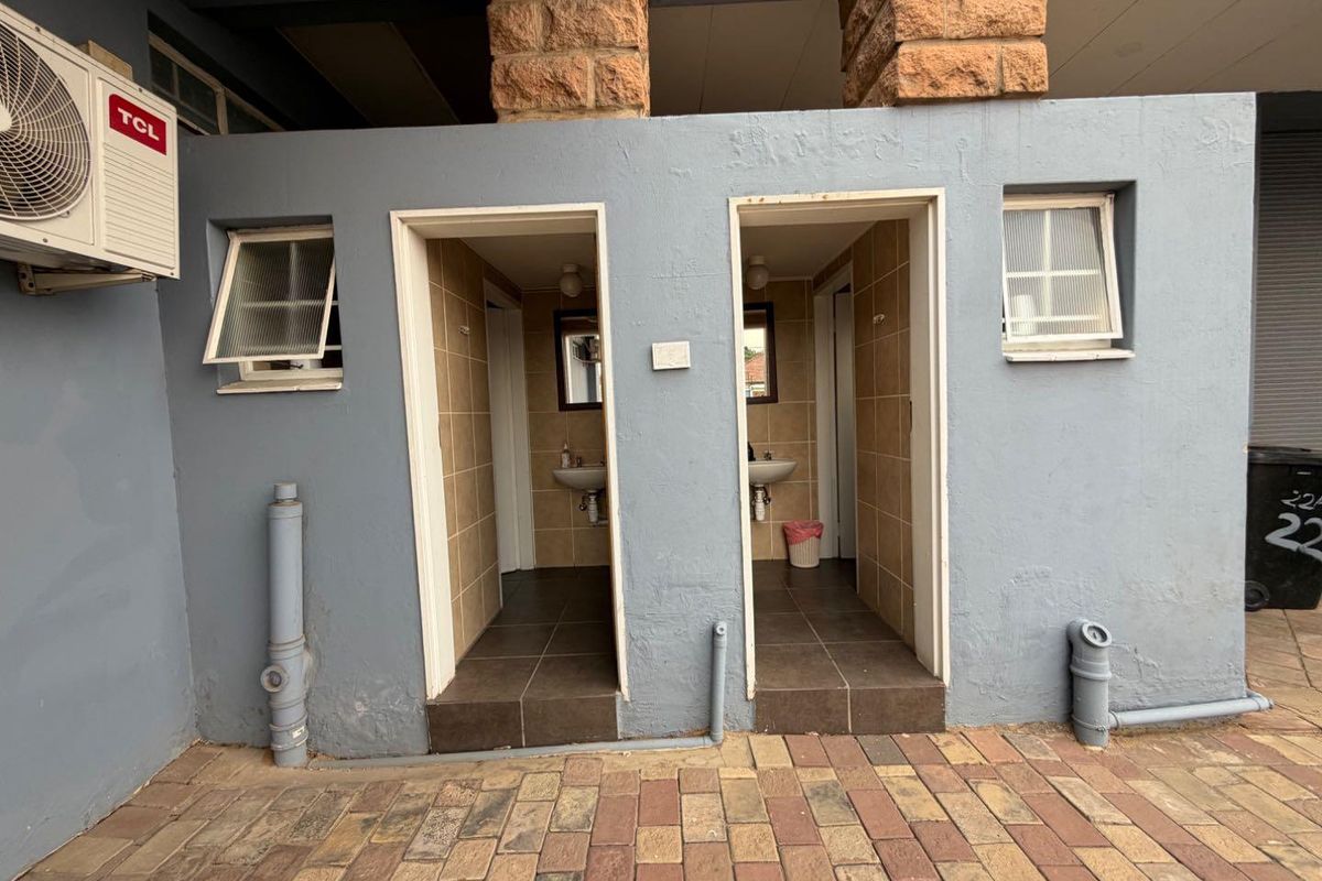 Exterior view of two separate bathroom entrances featuring tiled interiors, wall-mounted basins, and external plumbing fixtures.