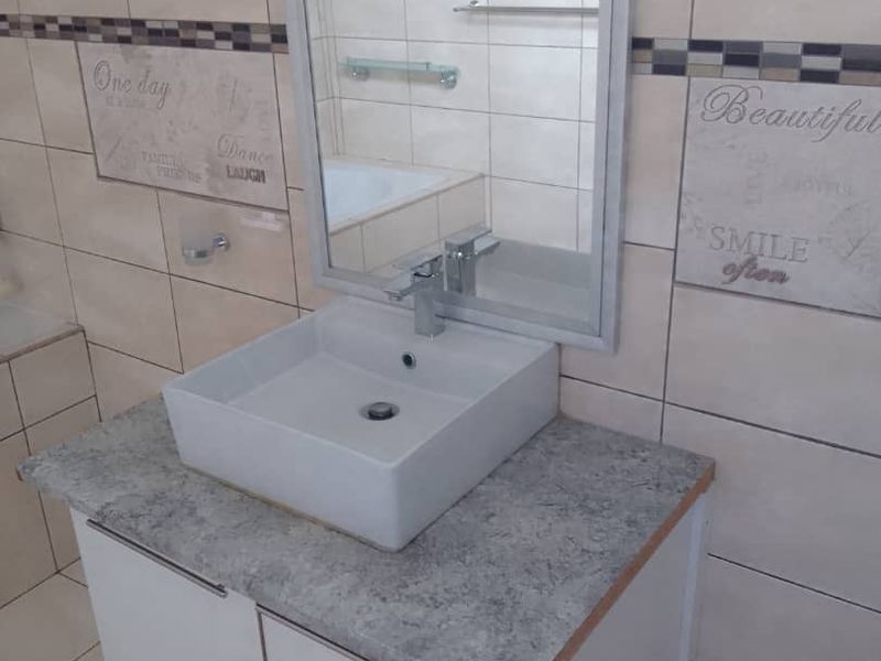 A bathroom featuring a modern vessel sink on a vanity cabinet with tiled walls and flooring.