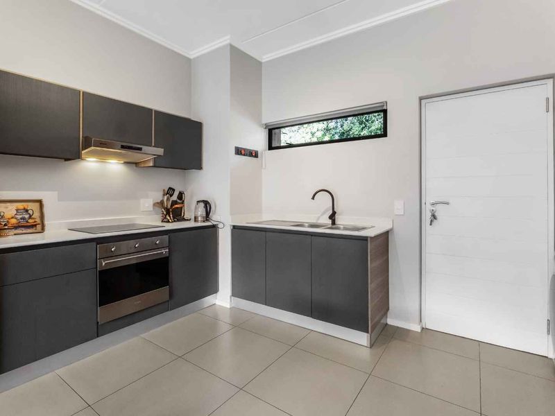 Modern kitchen featuring dark cabinetry, stone countertops, integrated appliances, and tiled flooring, offering a clean and functional workspace.