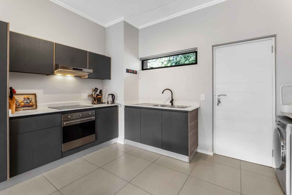 Modern kitchen featuring dark cabinetry, stone countertops, integrated appliances, and tiled flooring, offering a clean and functional workspace.