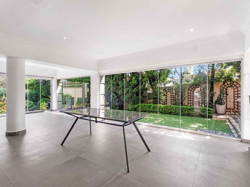 Spacious open-plan living area featuring large format floor tiles, recessed lighting, and expansive floor-to-ceiling glass doors providing seamless access to the garden.