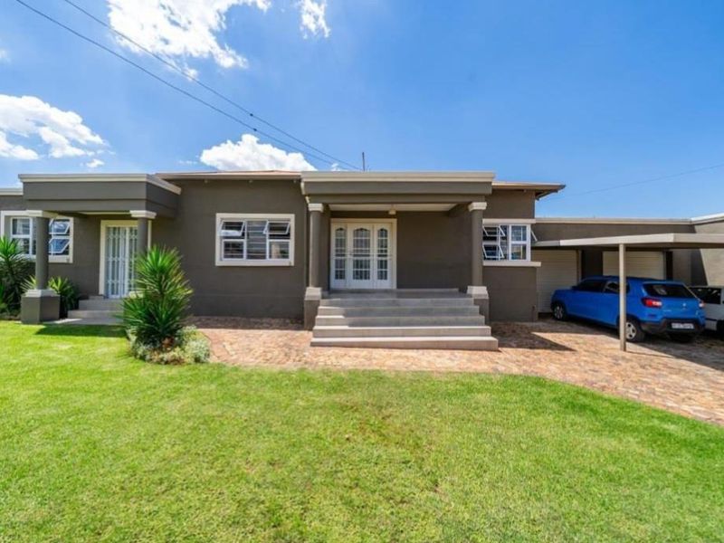 Front elevation of a well-maintained single-story house featuring a paved driveway, covered entrance porch, and an attached carport.